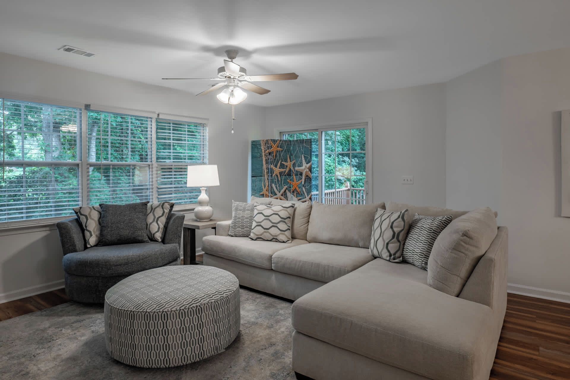 A living room with a sectional sofa, ottoman, and a ceiling fan.