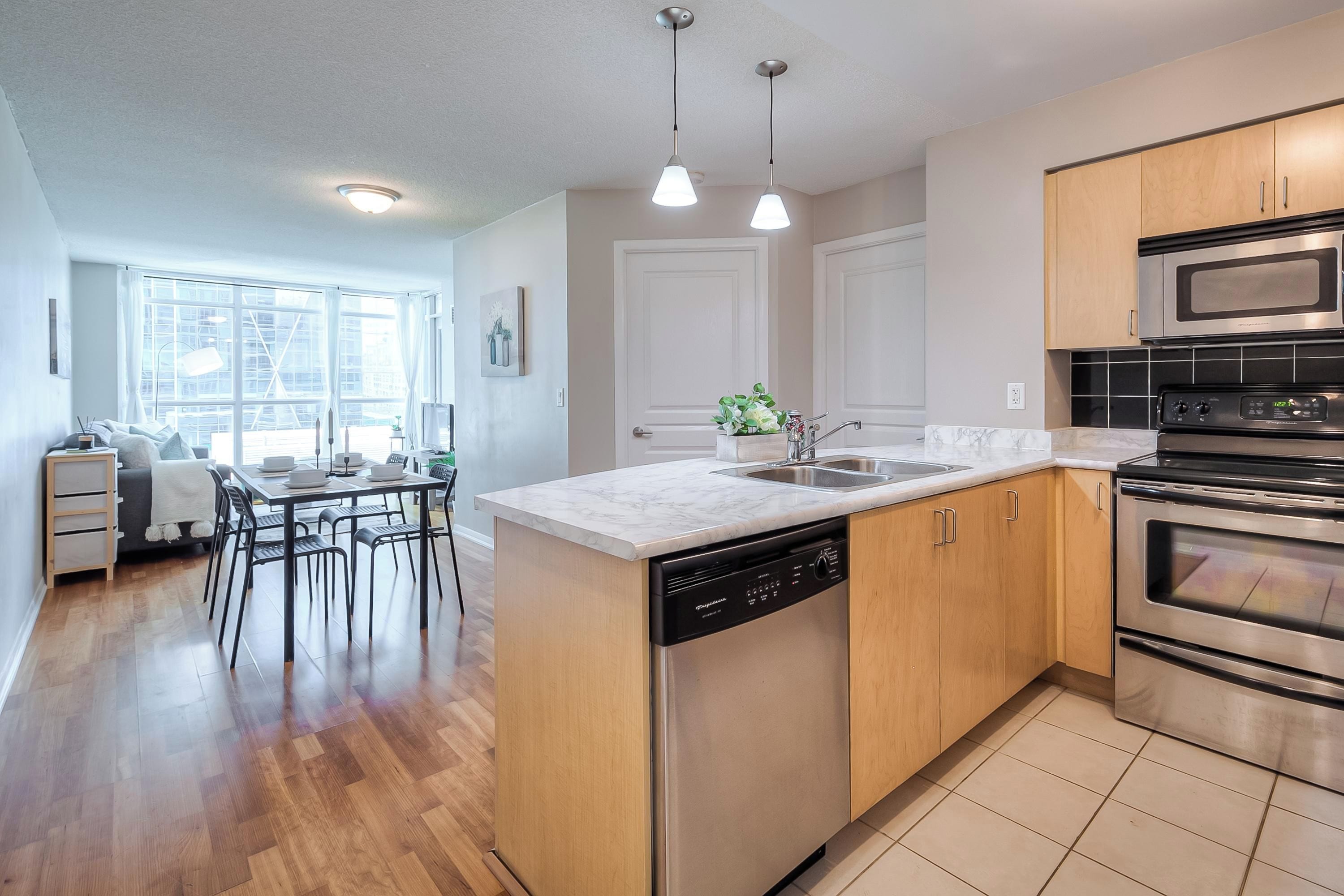 A modern kitchen with a dishwasher, double oven, and a dining area with a table and chairs.