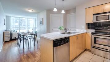 A modern kitchen with a dishwasher, double oven, and a dining area with a table and chairs.