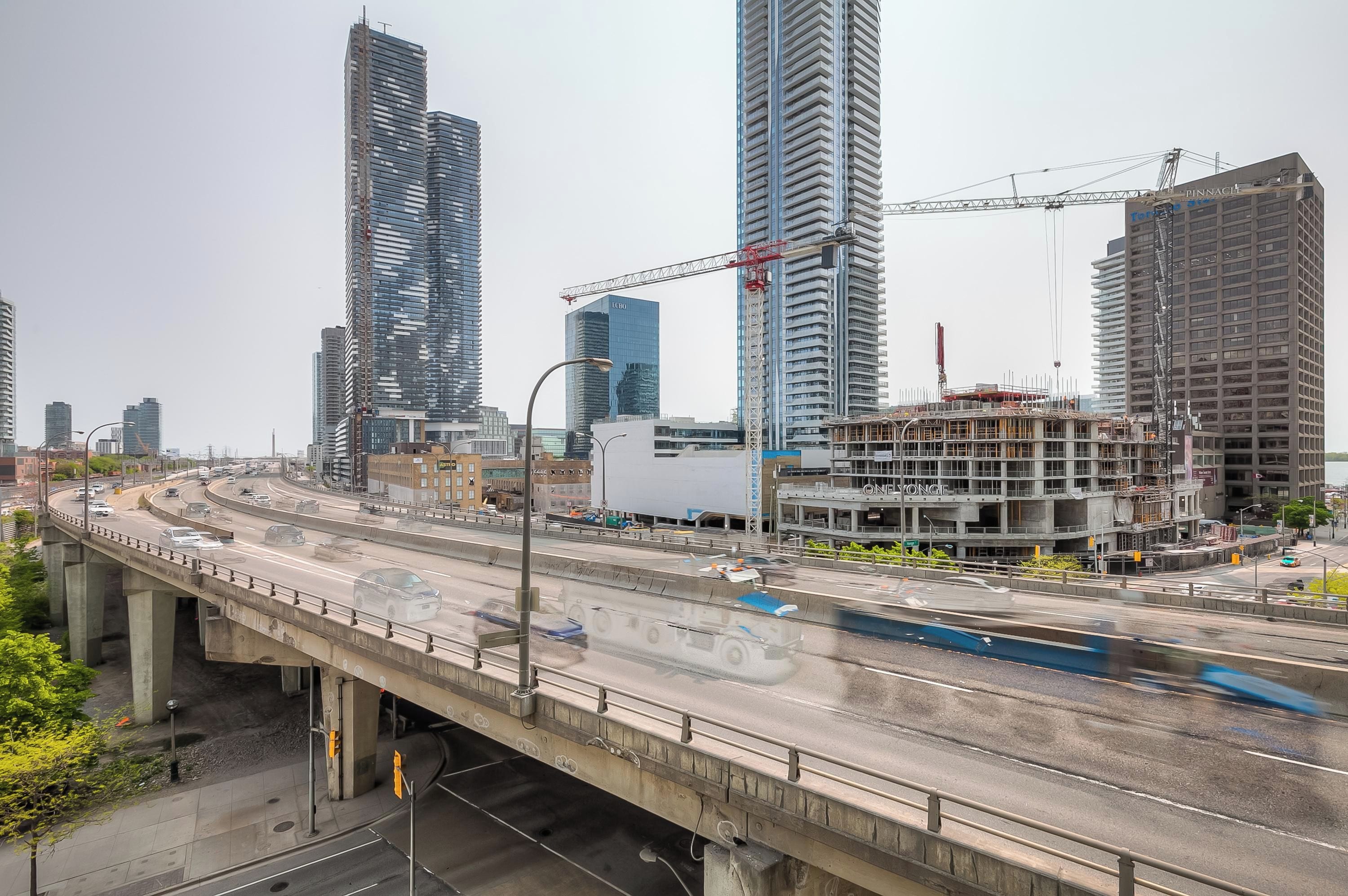 A multi-level highway with vehicles, a bridge, and high-rise buildings under construction.