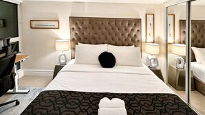 A hotel room with a large bed, two bedside tables with lamps, a desk with a chair, and a large mirror. - StayToronto - Union Station & Waterfront (Toronto)