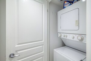 Una puerta blanca con manija plateada, una lavadora blanca y una secadora blanca apiladas encima.