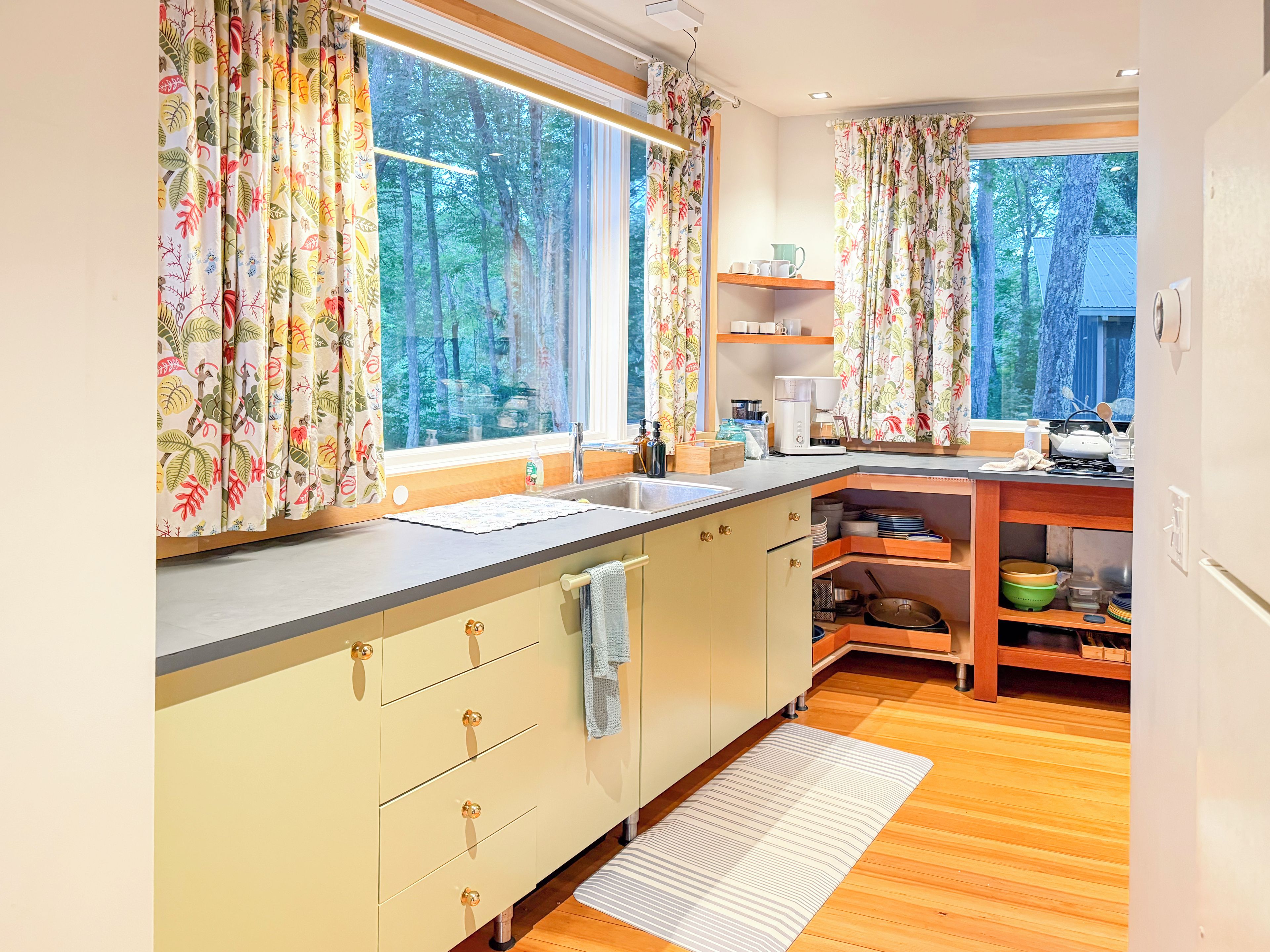 Une cuisine moderne avec un plan de travail en bois, un évier et une fenêtre agrémentée de rideaux.