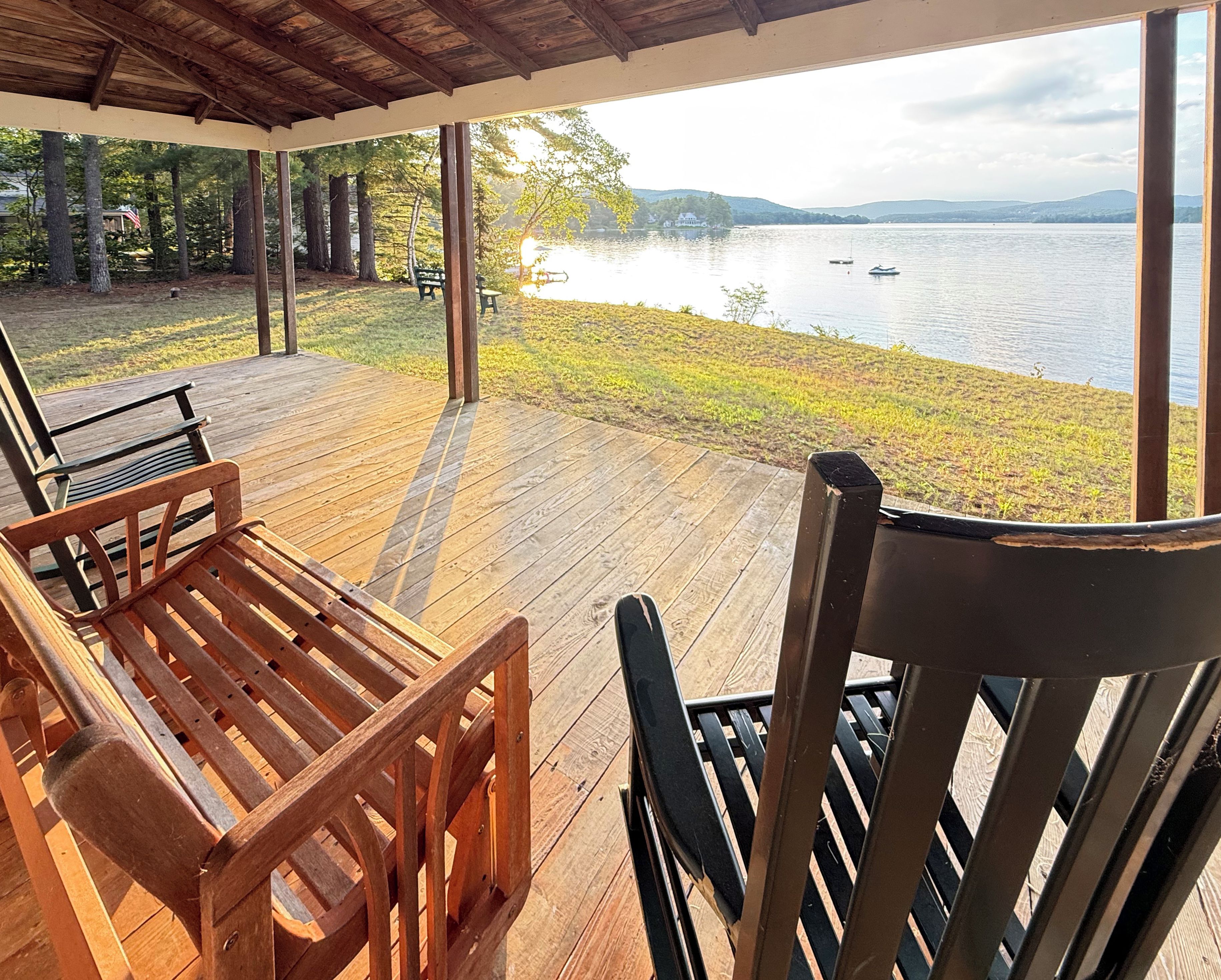 A wooden deck with outdoor furniture overlooking a lake.