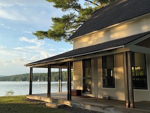 A lakeside house with a covered porch, large windows, and a view of the lake.