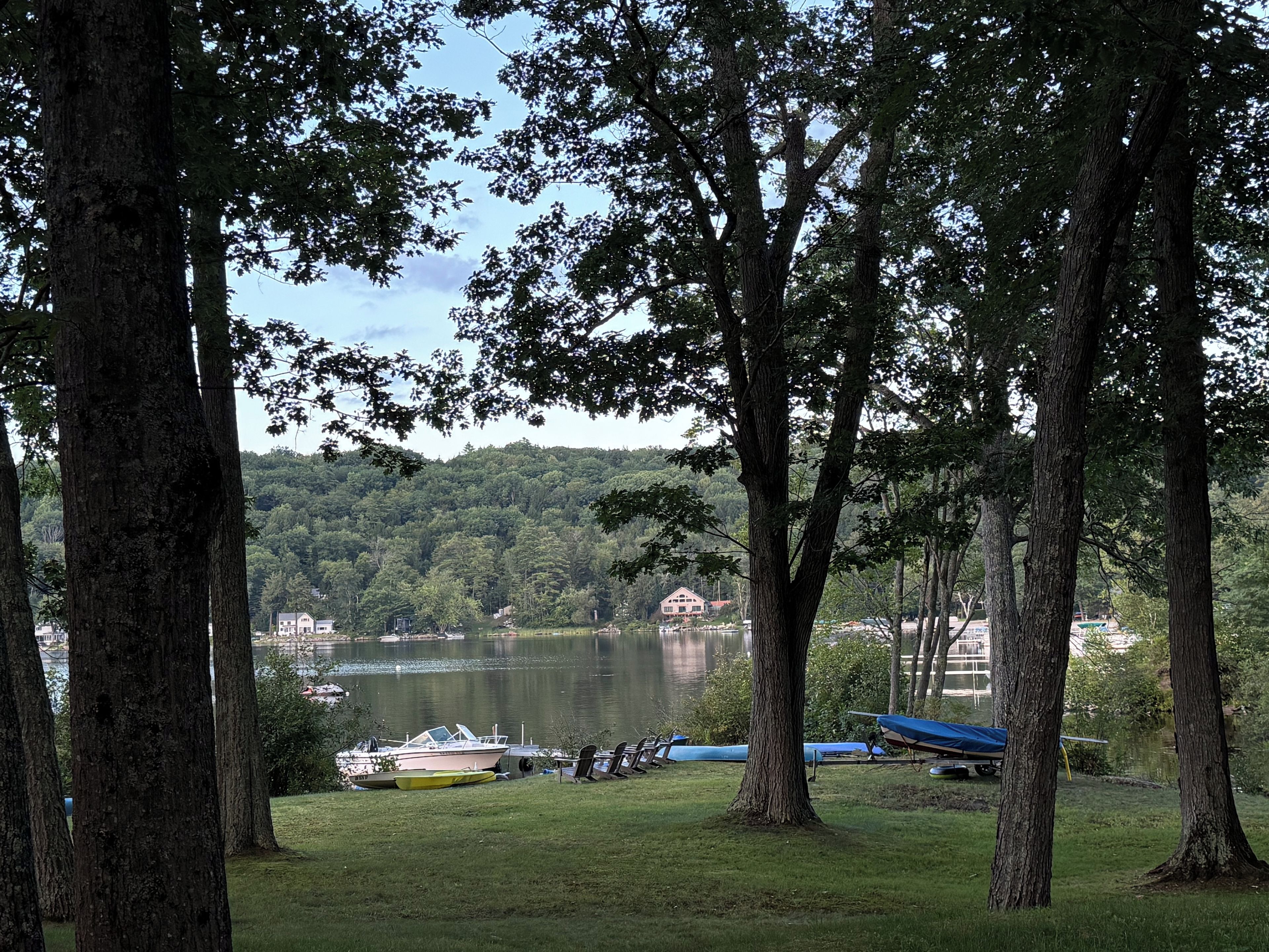 Une vue sur le lac, avec des bateaux amarrés, des arbres et un bâtiment situé au loin.
