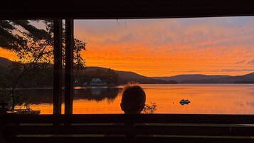 Une personne assise sur un banc, face à un lac, et contemplant le coucher de soleil.