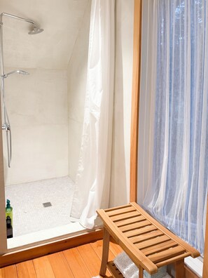 A shower area with a showerhead, curtain, and wooden bench. - The Shaker Cottage on Lake Mascoma (Enfield)