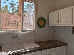 A kitchen with a window, white cabinets, and a marble countertop. - Charming Villa in Marrakesh with a garden and a swimming pool (Marrakesh)