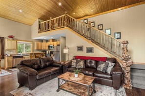 Un salon spacieux avec un plafond haut et un escalier en bois.