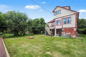 Ein zweistöckiges Haus mit Veranda und Feuerstelle im Garten.