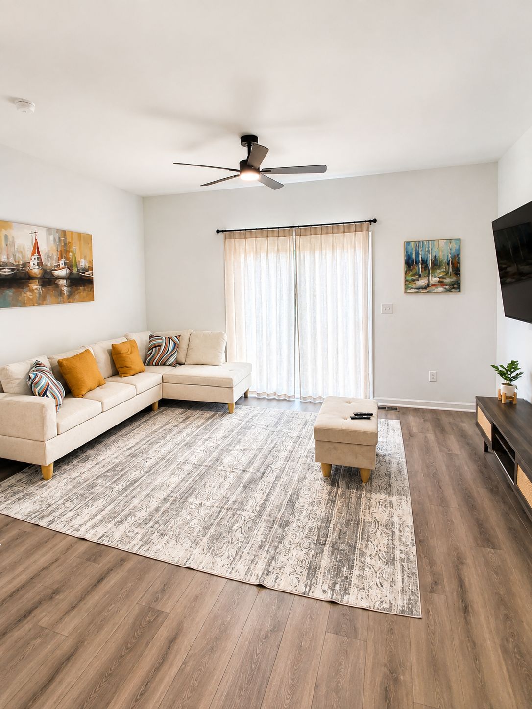 A living room with a sofa, ottoman, and a ceiling fan.