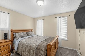 Ein Schlafzimmer mit einem hölzernen Bett, einem Nachttisch, einer Kommode und einem Deckenventilator.