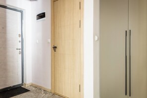 Um corredor com uma porta de madeira, uma porta branca e um guarda-roupa branco.
