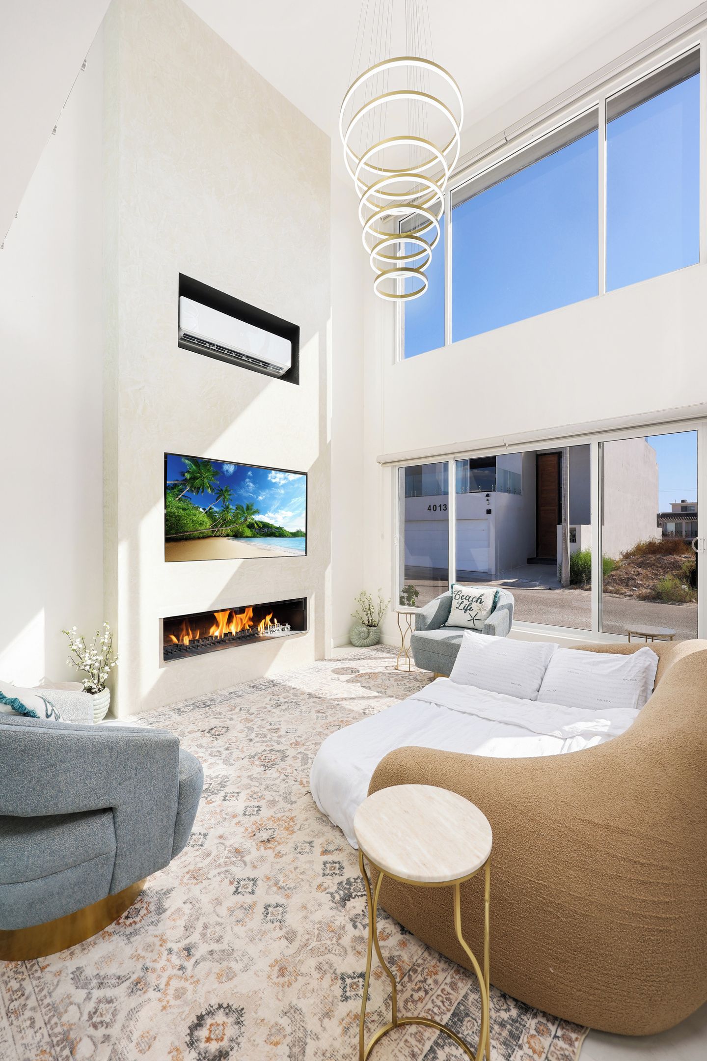 A modern living room with a fireplace, a large TV, and a view of the outside.