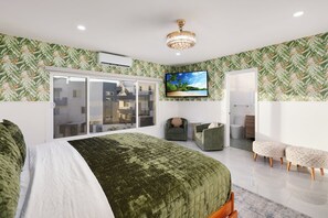 Ein modernes Schlafzimmer mit einem großen Bett, einem Fernseher, einer Schiebetür und tropisch gestalteter Tapete.