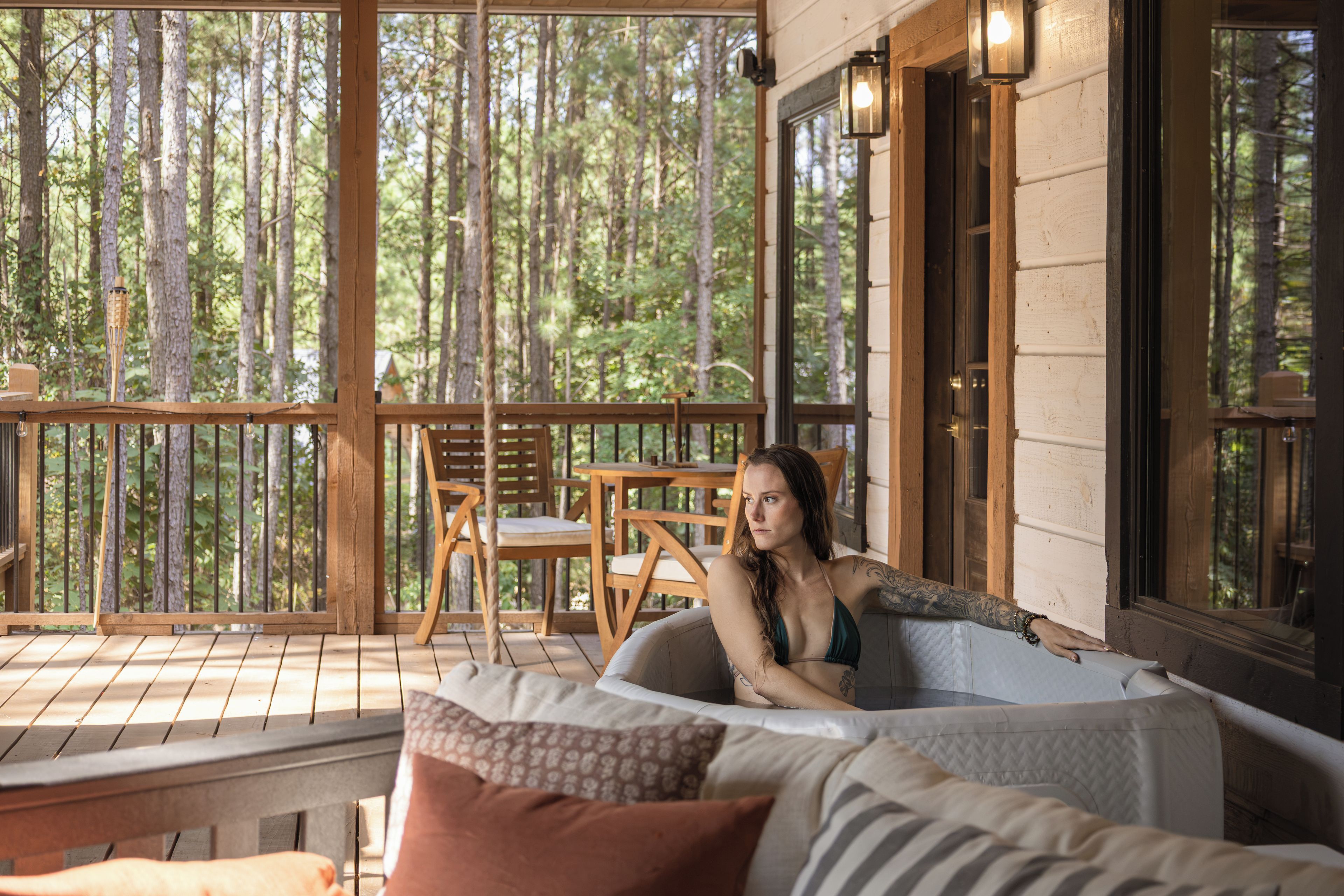 Eine Holzterrasse mit Whirlpool, Stühlen und einem Tisch.