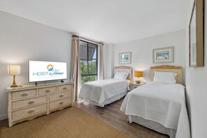 Een hotelkamer met twee bedden, een televisie, een dressoir en een raam met gordijnen.