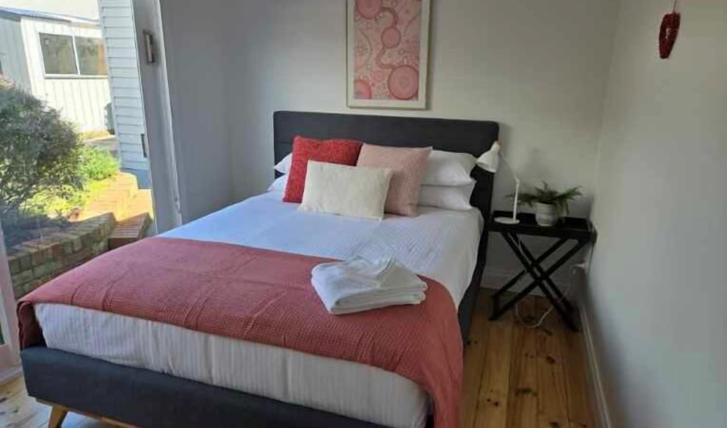 A bedroom with a bed, pillows, a bedside table, and a wall-mounted artwork.