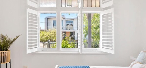 A room with a large window, a bed, and a potted plant.