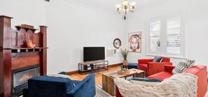 Ein Wohnzimmer mit Kamin, Fernseher und roten Sofas.