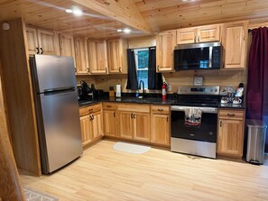 A kitchen with wooden cabinets, stainless steel appliances, and a black microwave.