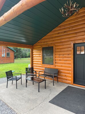 Eine Blockhütte mit einer Veranda und Sitzgelegenheiten im Freien, inklusive eines Kronleuchters aus Hirschgeweihen.