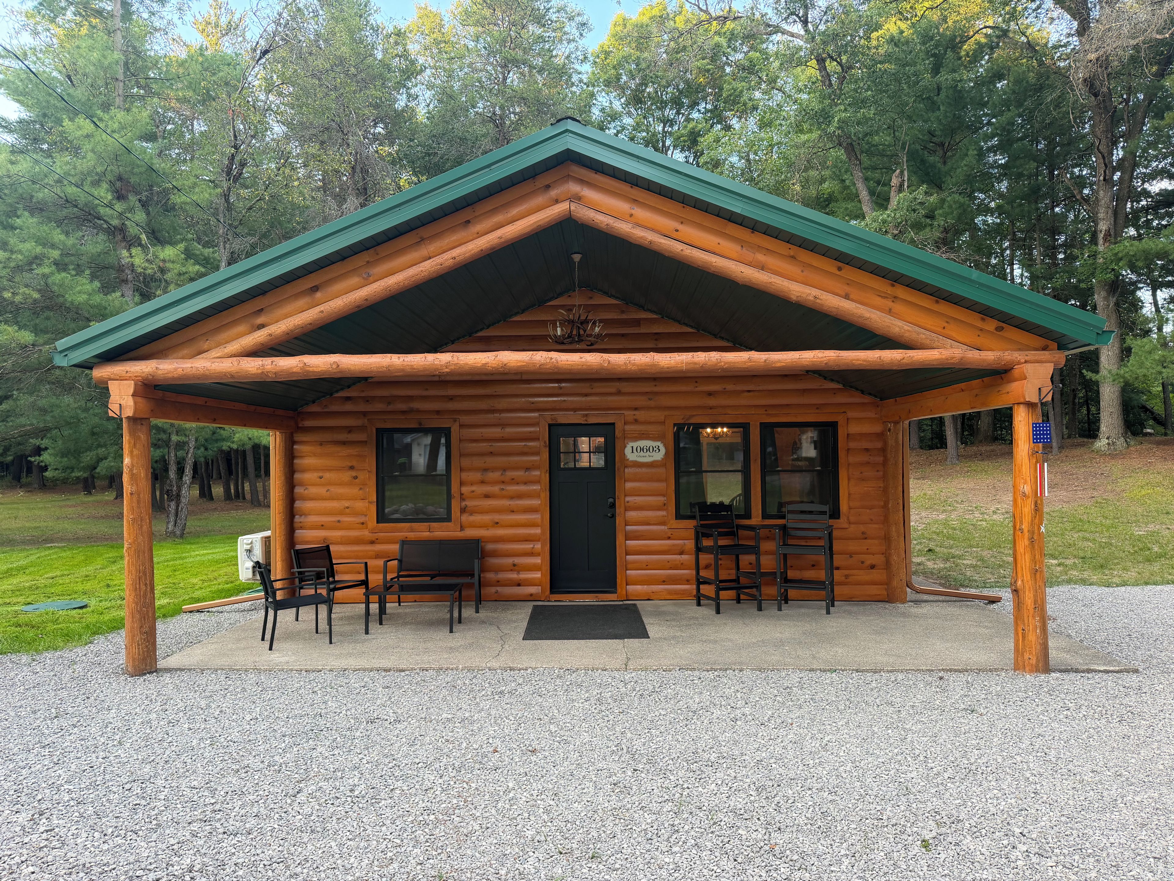 Eine Blockhütte mit verdeckter Veranda, zwei Fenstern und einer Tür.