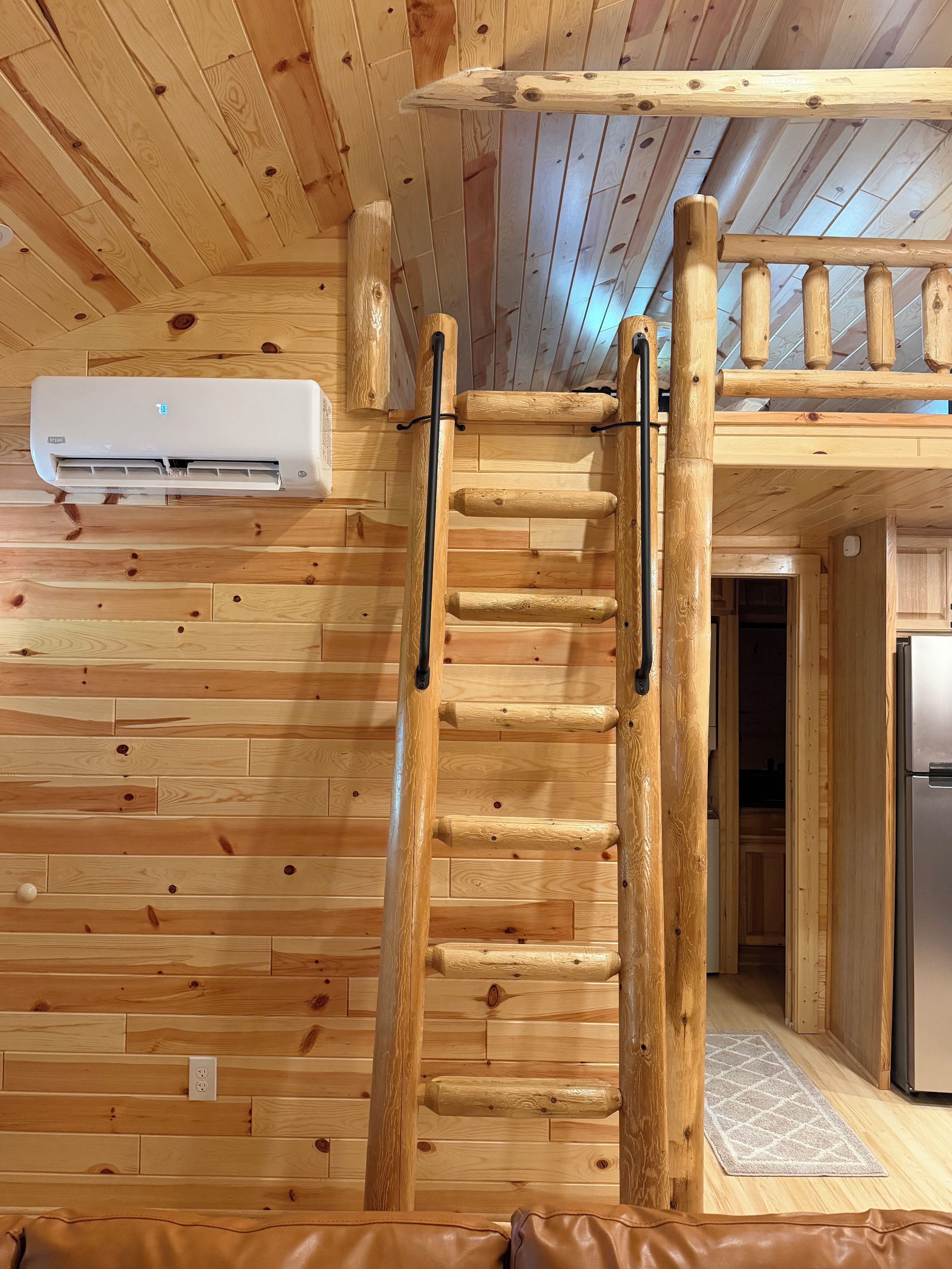 Un interior de madera con una escalera, un equipo de aire acondicionado y una zona de cocina.