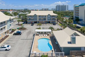 Ein Hotel mit Swimmingpool, mehreren Balkonen und einem Parkplatz.