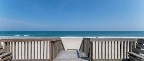 Una pasarela de madera que conduce a una playa con vista despejada al océano.