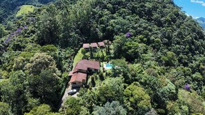 A house with a swimming pool surrounded by dense forest. - Pousada Jardim Real (Nova Friburgo)