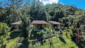 A two-story house with a tiled roof, surrounded by lush greenery and trees.