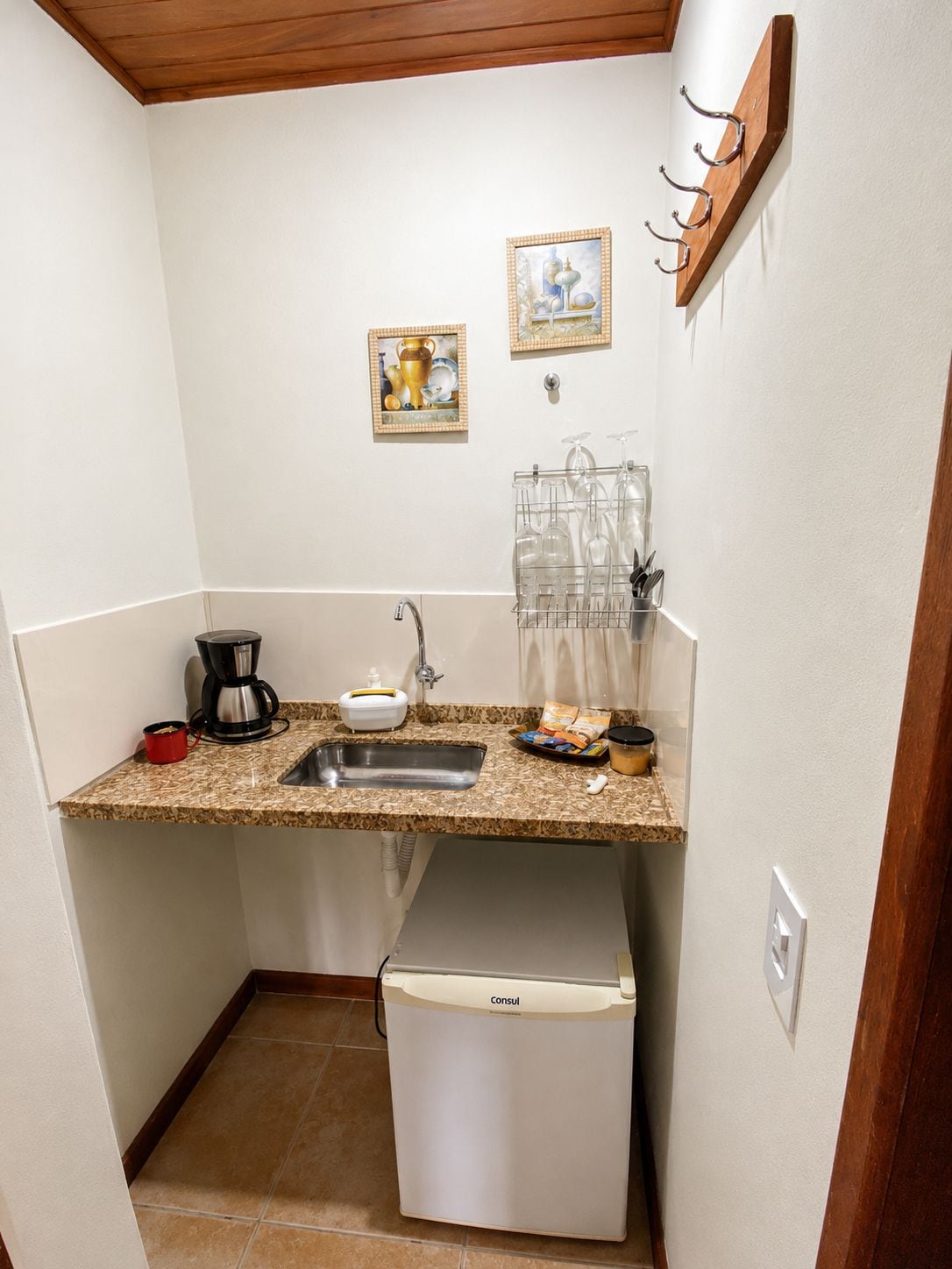 Una cocina compacta con lavabo, cafetera y refrigerador pequeño.