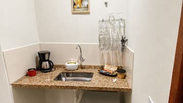 A compact kitchen with a sink, coffee maker, and a mini fridge.