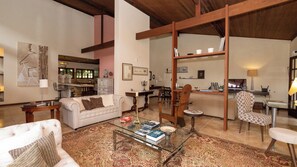 A spacious living area with a sofa, armchairs, a coffee table, and a dining area with chairs and a table.