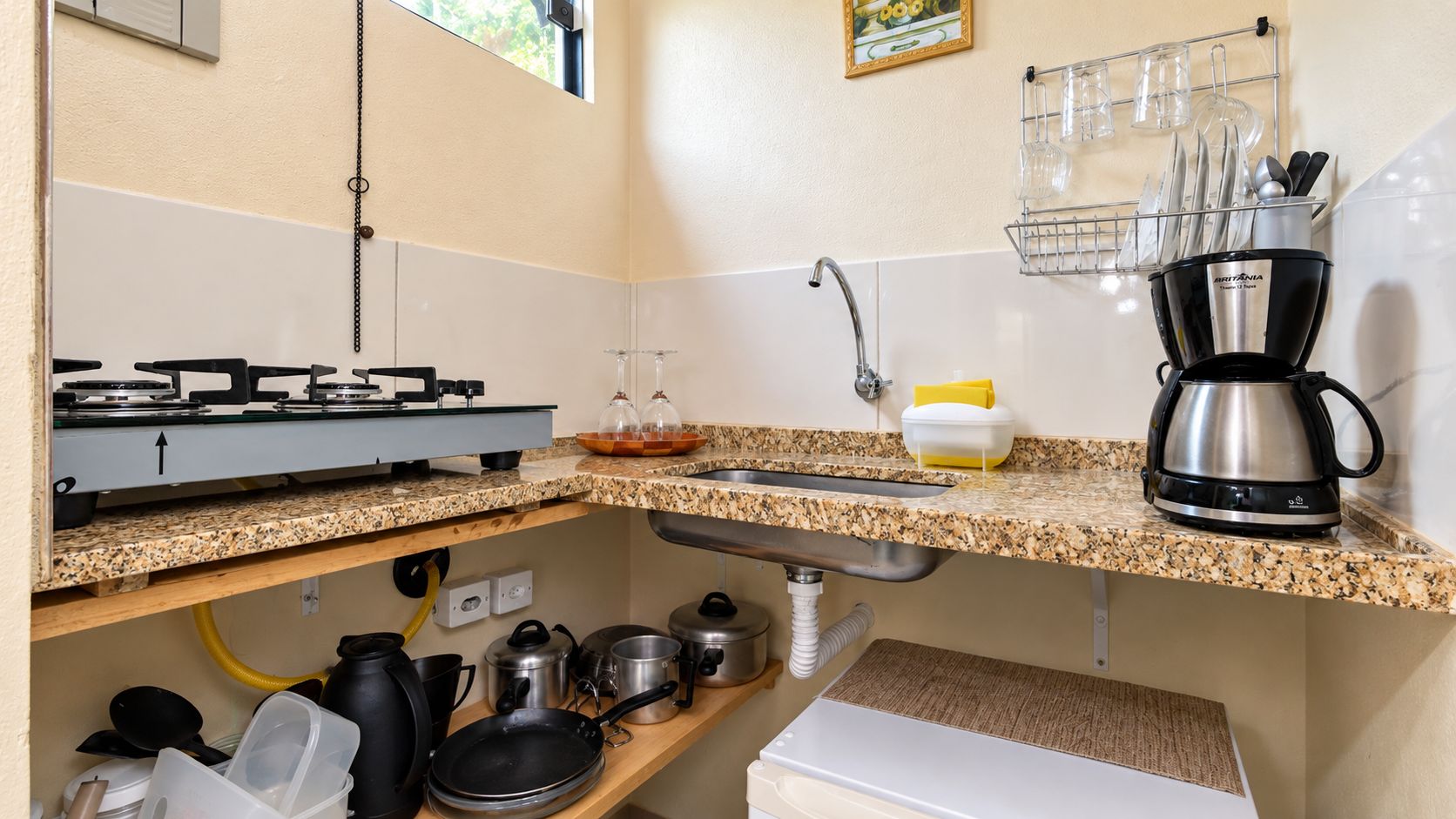 A kitchen with a gas stove, sink, and a coffee maker.