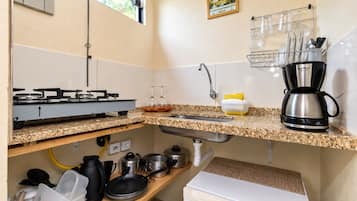 A kitchen with a gas stove, sink, and a coffee maker.