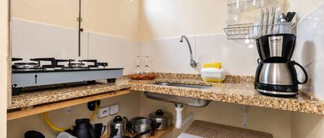 A kitchen with a gas stove, sink, and a coffee maker.