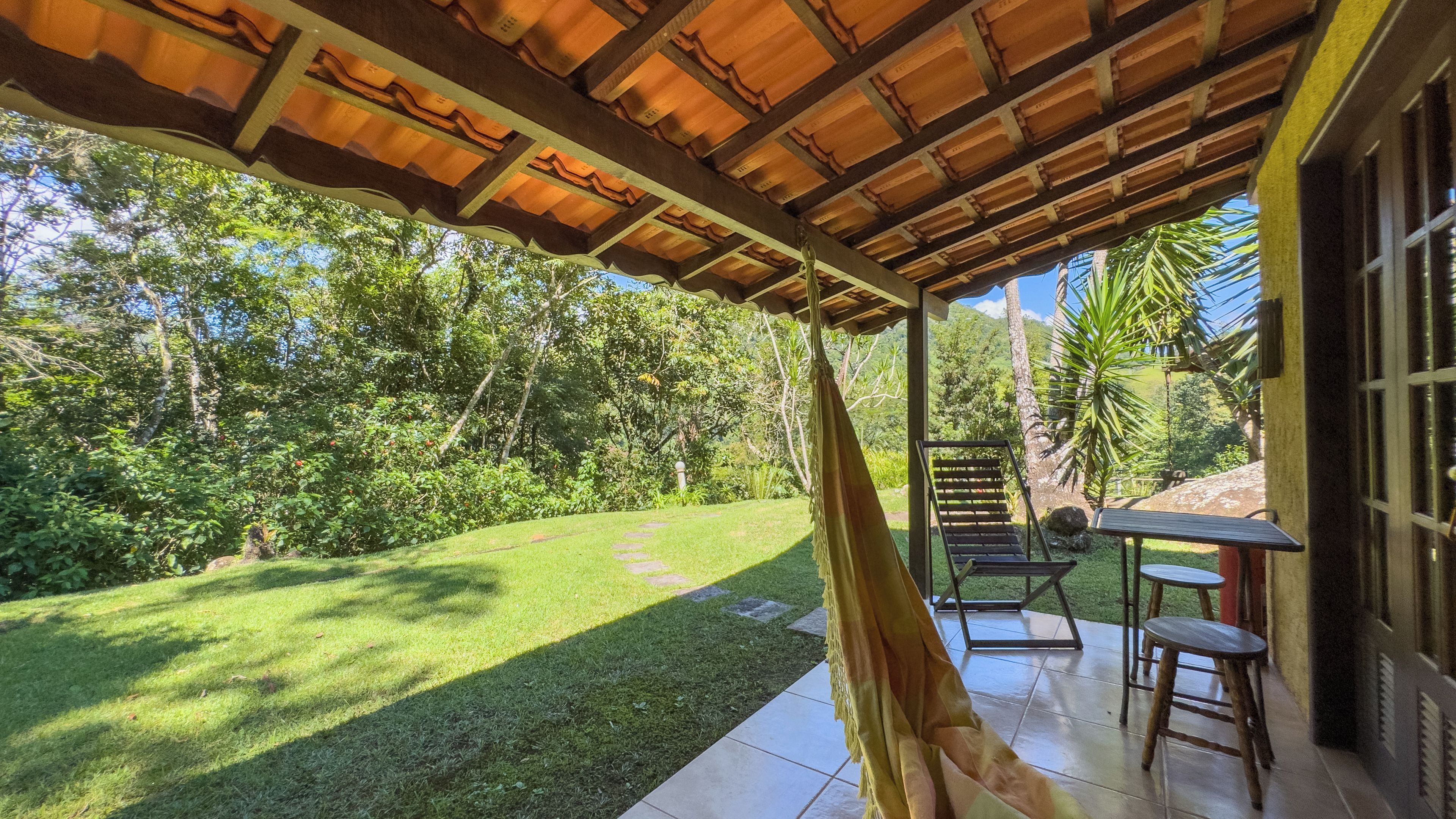 A covered patio with a view of a lush garden and a wooden pergola.