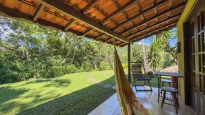 A covered patio with a view of a lush garden and a wooden pergola.