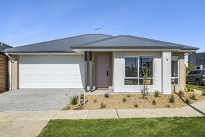 Ein modernes, zweistöckiges Haus mit Garage, Eingangstür und einem kleinen Garten.