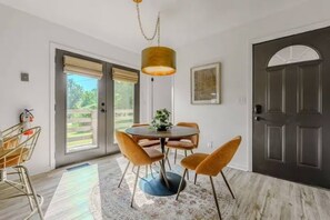 A dining area with a round table, four chairs, a hanging light fixture, and a door with a window view. - Vantara Smoky Views - Feels like home (Sevierville)