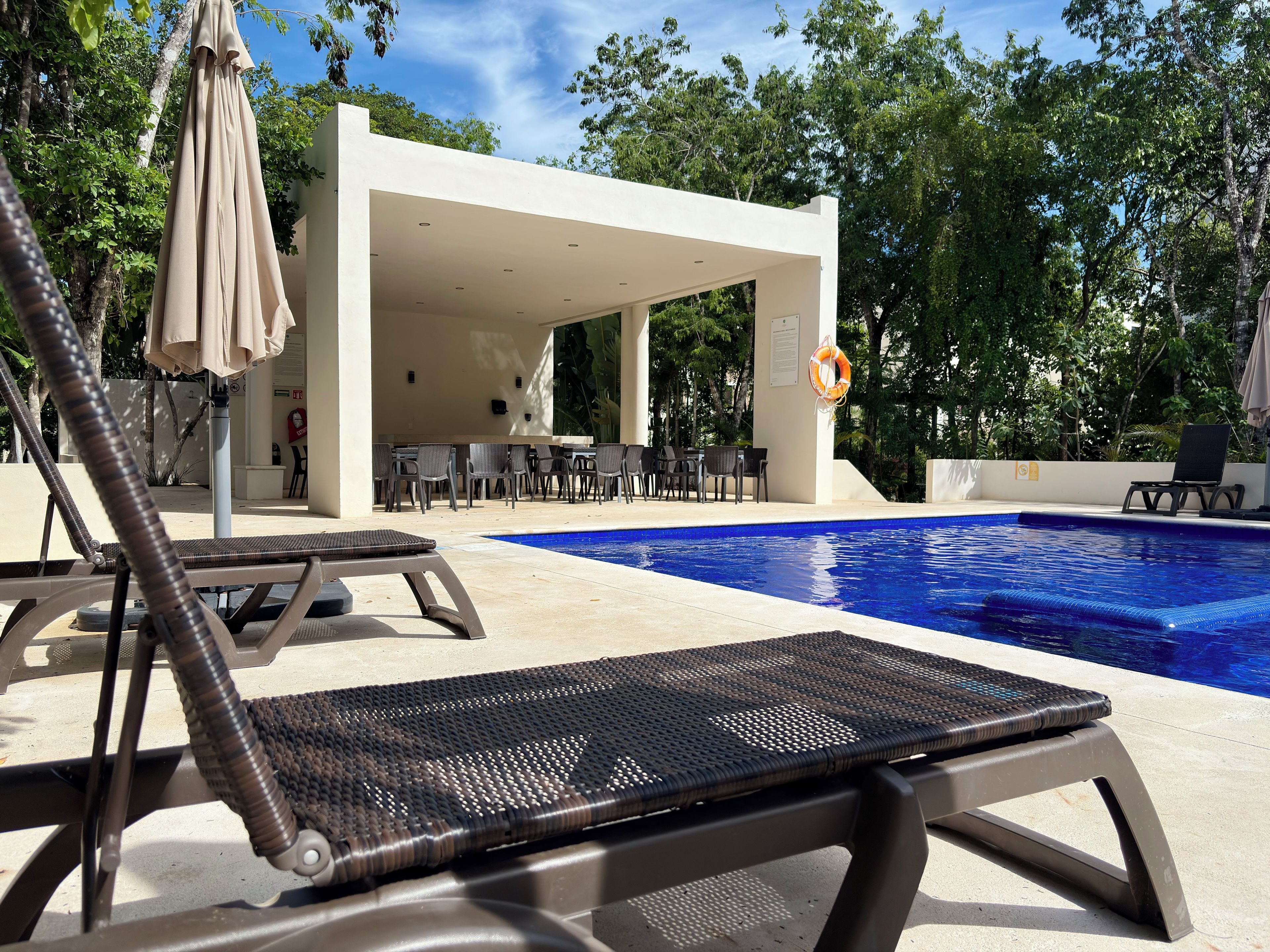 Un espace aménagé au bord de la piscine, avec des chaises longues, un coin salon abrité et une bouée de sauvetage.