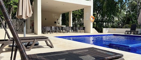 A poolside area with lounge chairs, a covered seating area, and a lifebuoy.