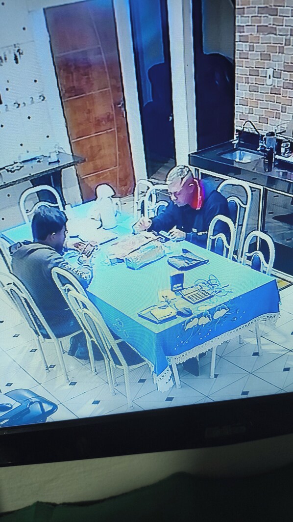 A dining area with a table set for two, chairs, and a tiled floor.