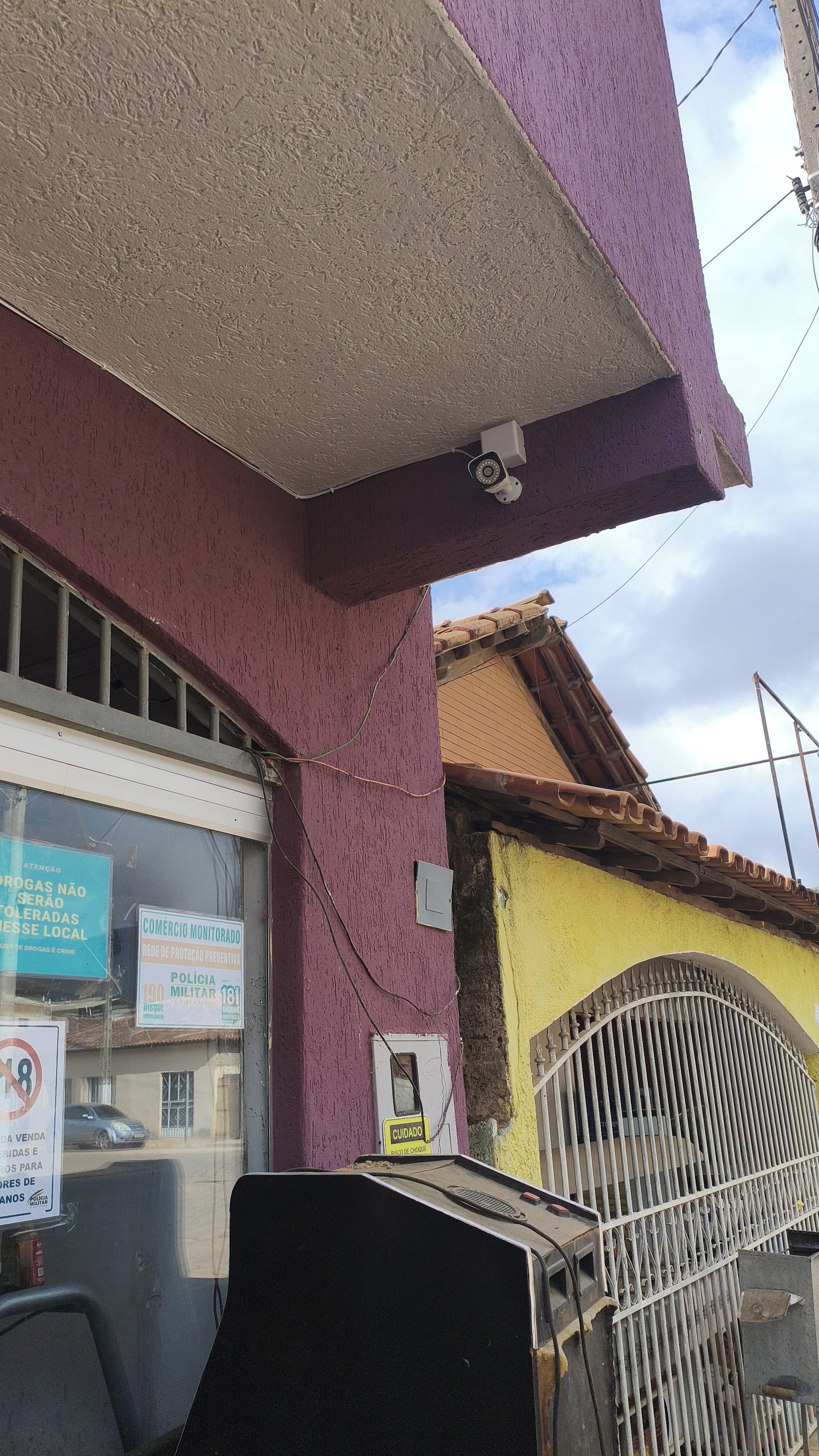 Un edifici amb una càmera de seguretat, una reixa i una finestra amb un rètol.