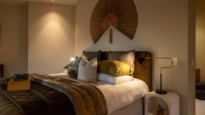A bedroom with a bed, pillows, a bedside table, and a wall-mounted fan. - The Distiller's Retreat (Takaka)