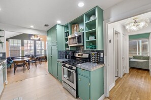 Cozinha com fogão, micro-ondas e armários. Há uma área de jantar com mesa e cadeiras.