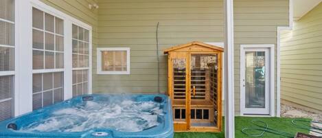 A hot tub in a covered outdoor area with a wooden structure and a door.